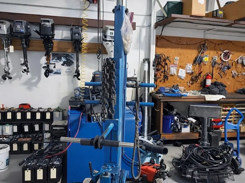 Inside the PK Marine Service workshop in Bristol, RI — outboard motors, engine repair stand, and marine workbench